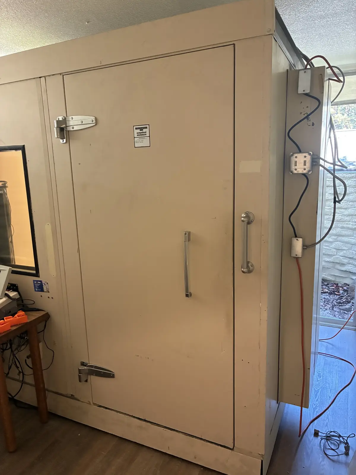 A fully assembled audiometric sound booth with its door closed, installed in its new room
