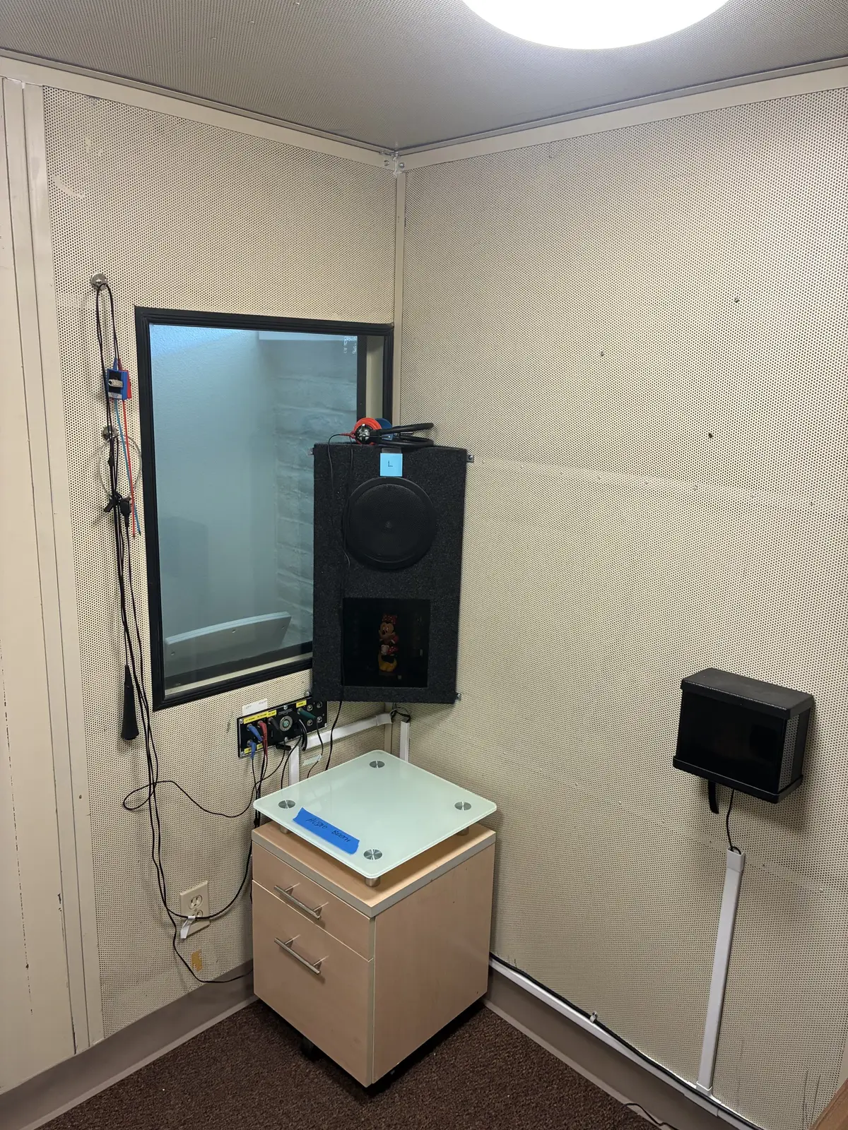 Inside a rebuilt sound booth: a sound-field speaker mounted beside the booth window
